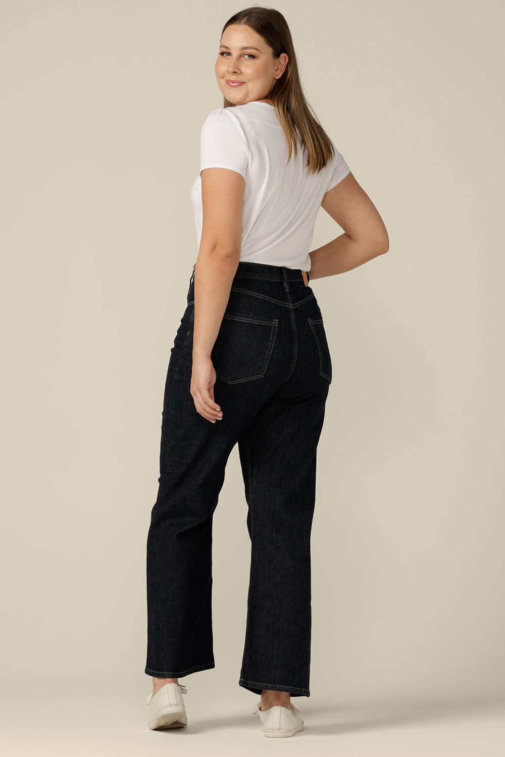 Well-fitting conscious jeans wear by Australian and New Zealand women's clothing brand, L&F, these are high-waisted, flared leg jeans in midnight denim, worn with a white bamboo jersey top.