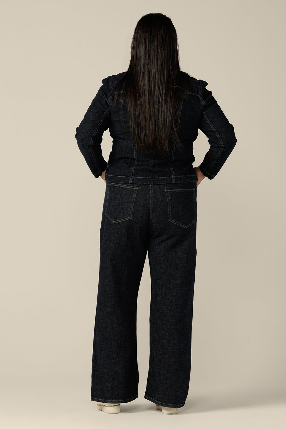 Back view of ethical and sustainable jeans wear made for women in sizes 8 to 24, these jeans are high-waisted, with flared legs. Worn here with a denim jacket, in a size 16, these conscious jeans by Australian and New Zealand women's clothing brand, L&F are tailored to fit women's curves.