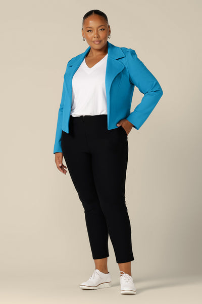 A size 18, fuller figure woman wears the Garcia Jacket in Opal blue ponte fabric by Australian and New Zealand women's clothing brand, L&F. Featuring collar and notch lapels and long sleeves, this open-fronted jacket is worn with a white bamboo jersey top and slim-leg, cropped black pants as a sporty, casual jacket.