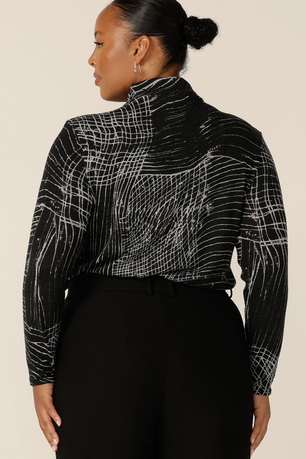 Back view of a fuller figure woman wearing a long sleeve, woolly knit turtleneck top, size 18, in an abstract black and white pattern. A warm winter top, this women's polo neck top by Australian and New Zealand women's clothing label, L&F is available to shop in inclusive size range of sizes 8-24..