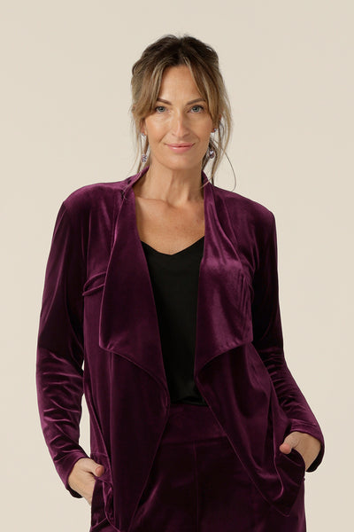 Occasionwear dressing at its finest, this soft tailoring jacket in red wine velour adds effortless glamour to black cocktail wear. Shown here over a black cami top and slim leg black trousers, this open front, soft collared evening jacket is made in Australia in sizes 8 to 24.