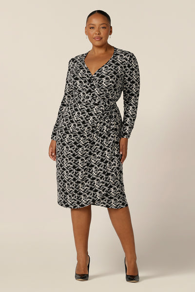 A long sleeve, black and white print, wrap dress with tulip skirt by Australian and New Zealand women's clothing label, L&F. Worn by a fuller figure woman, this jersey wrap dress is available in inclusive sizes, 8 to 24.