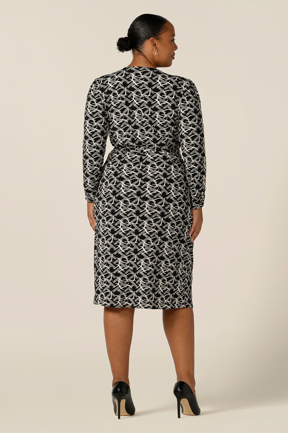 Back view of a long sleeve, black and white print, wrap dress with tulip skirt by Australian and New Zealand women's clothing label, L&F. Worn by a plus size woman, this jersey wrap dress is available in inclusive sizes, 8 to 24.
