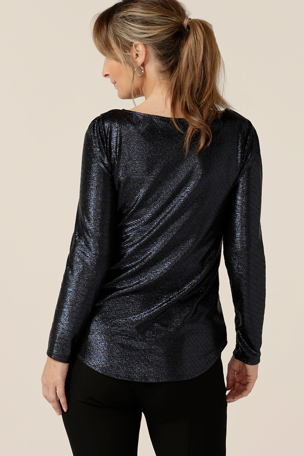 Back view of a size 10, 40-plus woman wearing a shimmering midnight blue, sparkly top with high scoop neck and long sleeves. Simple and easy-to-wear, this comfortable evening top is made in Australia in sizes 8 to 24.