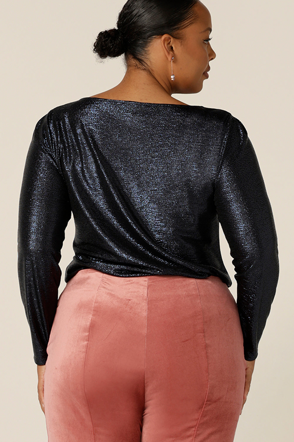 Back view of a fuller figure, size 18 woman wears a sparkly top in shimmering midnight blue jersey top. With a high scoop neck and long sleeves, this modest eveningwear top is great for plus size and 40 plus fashionable women.