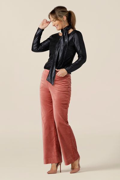 Evening and cocktail wear gets a touch of disco with these flared leg, tailored pants in musk pink velveteen. Worn with a sparkly blue, long sleeve top and neck tie for eveningwear, these special event pants are made in Australia in sizes 8 to 24, petite to plus sizes.