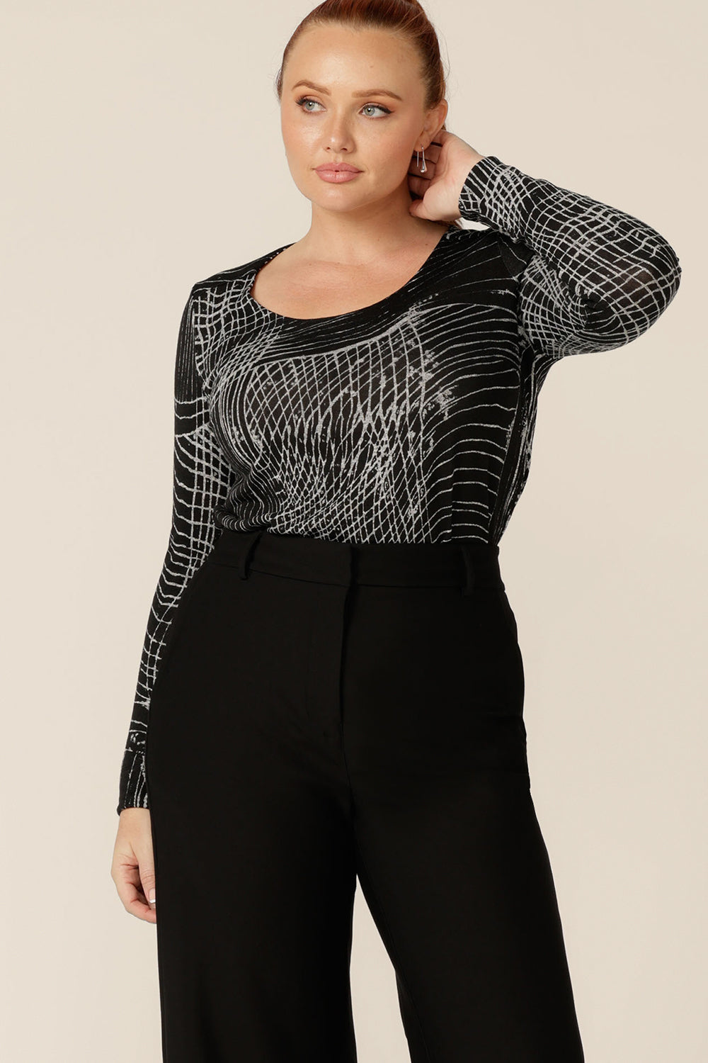 A curvy woman wears a long sleeve, round neck top in size 12. This is the Leith Top by Australian and New Zealand women's clothing label, L&F, ad is worn with a high waisted, black pants. A good top for work and weekend wear, tailored details enhance this top's black and white patterned, textured knit fabric.
