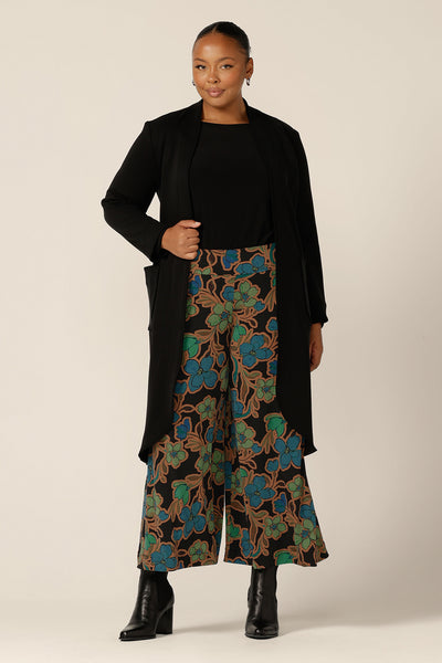 Great for chic city style, this black coat layers well for commuter workwear and travel. A curvy size 12 woman wears this softly tailored black trenchcoat in modal fabric with printed wide leg pants and a black jersey boat neck top. Shop all online at size-inclusive women's clothing brand, L&F.