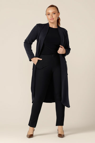 A size 12 woman wears the Marant Trenchcoat in Bluestone by Australian and New Zealand women's clothing company, L&F. A collarless, open fronted coat with tie belt and patch pockets, this classic navy jacket makes for an elegant yet warm autumn/winter coat.