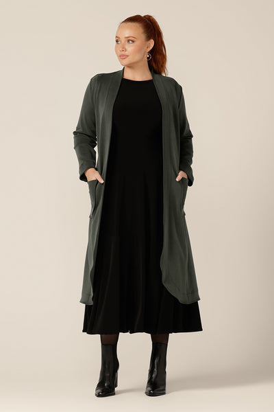 A classic winter coat for women, the Marant Trenchcoat in Sage green by Australian and New Zealand womenswear brand, L&F is shown in a size 12, and worn with a black jersey dress. A collarless, open fronted coat with tie belt and patch pockets, this women's winter jacket is available to shop in sizes 8 to 24.