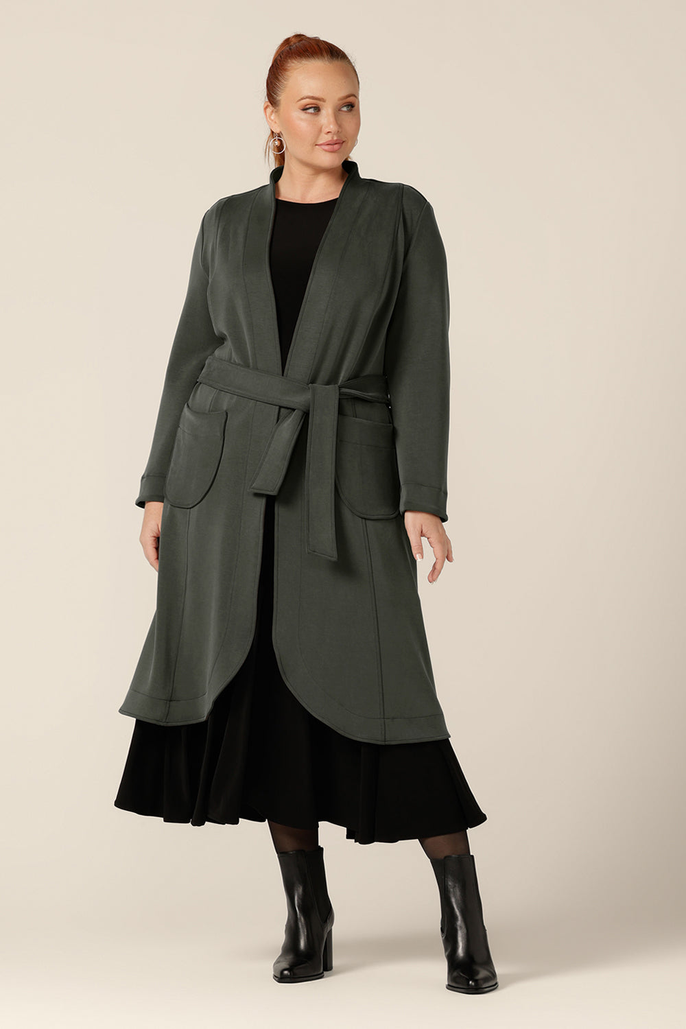 A classic winter coat for women, Marant Trenchcoat in Sage green by Australian and New Zealand women's clothing brand, L&F is shown in a size 12, and tied with a belt at the waist. A collarless, open fronted coat with tie belt and patch pockets, this classic green coat is avaiable to shop in an inclusive 8 to 24 size range.