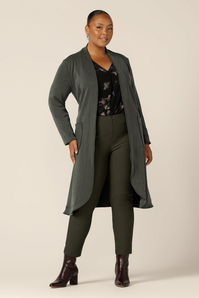 A plus size, size 18 woman wearing a long sleeve, V-neck top in printed black jersey with slim-leg, olive green pants and a long, sage green jacket. Made in Australia by Australian and New Zealand women's clothing label, L&F, this comfortable top is good for work and casual wear.