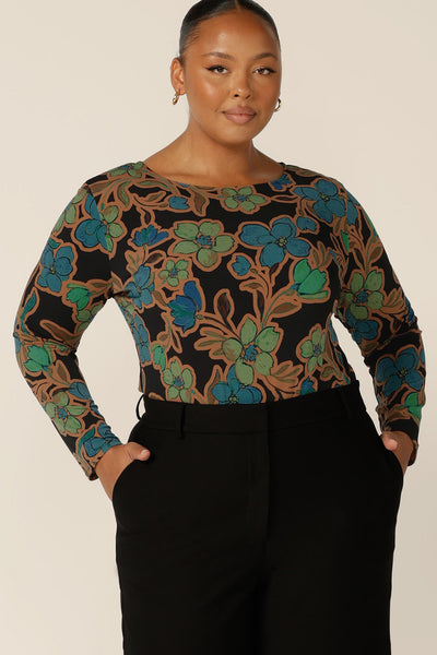 A plus size, size 18 woman wears a boat neck jersey top with long sleeves. In an opulent floral print, this slim-fit jersey top sits well under jackets for workwear. 