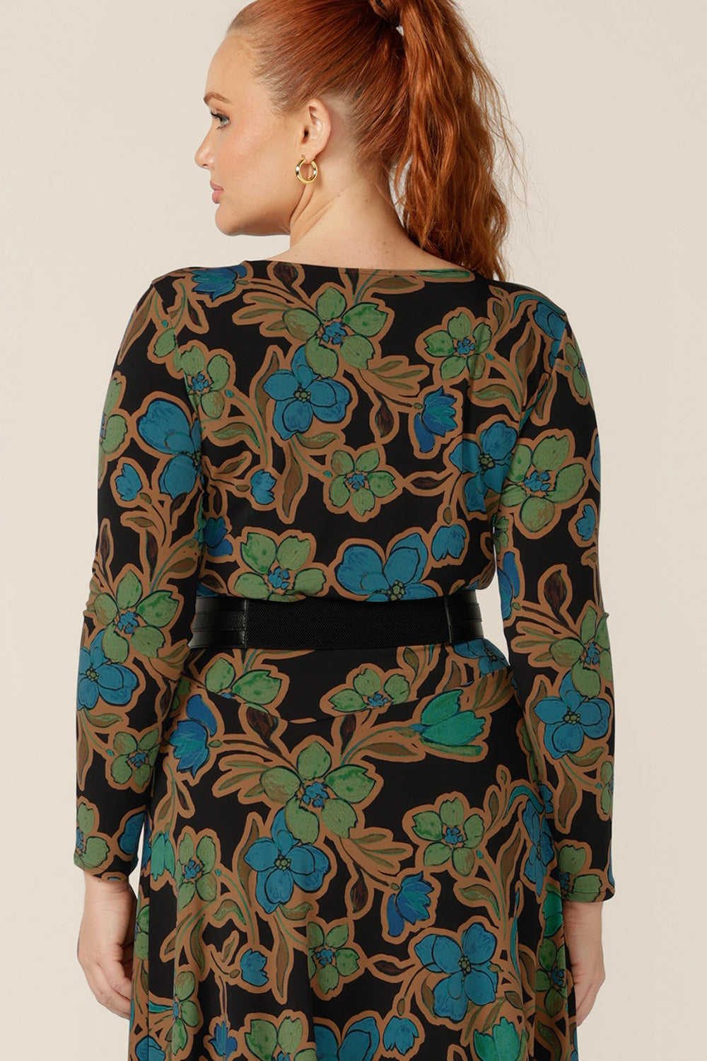Back view of a size 12, curvy woman wearing a floral print, boat neck top with long sleeves with a an asymmetric skirt and black belt to create a faux dress effect. Both are made in Australia by size inclusive clothing label, L&F.