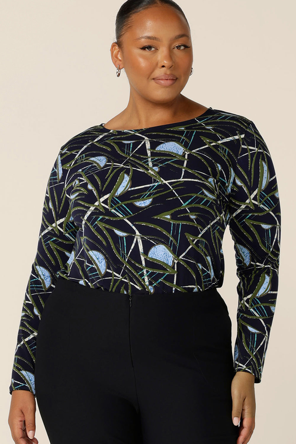 a size 18, plus size woman wears a long sleeve, boat neck top by Australian and New Zealand women's clothing brand, L&F. Featuring a blue, green and white print on a navy jersey base, this top is a great top for work and corporate wear.