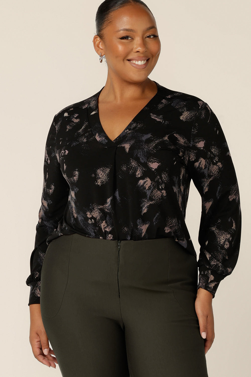 A plus size, size 18 woman wears a long bishop sleeve, V-neck top in printed black jersey. Made in Australia by Australian and New Zealand women's clothing company, L&F, this women's top is good for workwear and casual wear. 