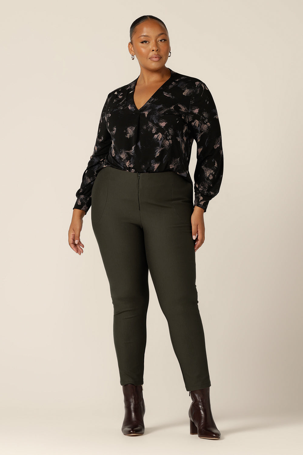 A plus size, size 18 woman wearing a long sleeve, V-neck top in printed black jersey with slim-leg, olive green pants. Made in Australia by Australian and New Zealand women's clothing label, L&F, this comfortable top is good for work and casual wear.