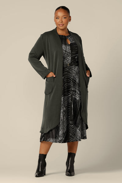 A good dress for plus size, fuller figure women, the Sandee Dress by Australian and New Zealand womenswer lable, L&F is well-fitting in a black and white, stretch knit fabric. A midi length, long sleeve dress with twisted keyhole detail, this warm winter dress is worn with a soft trench coat in sage green modal.