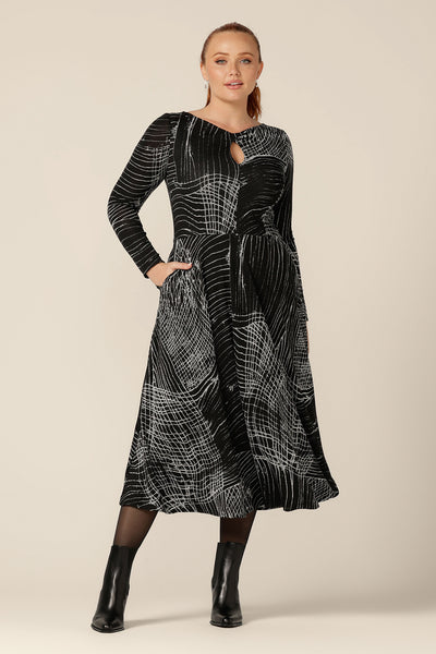 A size 12, curvy woman wears a midi length, long sleeve dress with twisted keyhole detail. Made by Australian and New Zealand women's clothing label, L&F in an inclusive size range of sizes 8 to 24.