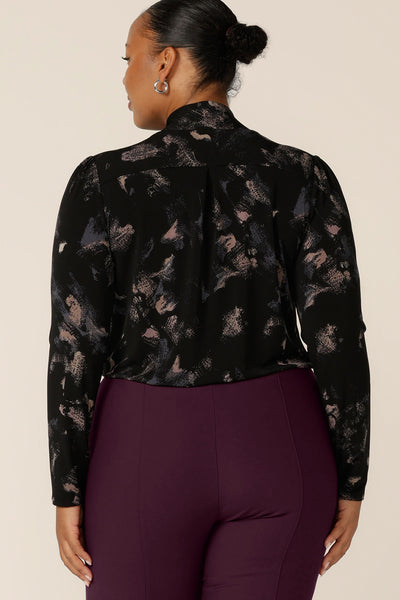 Back view of a plus size, size 18 woman wearing a long sleeve, V-neck top with tie neck detail by Australian and New Zealand women's clothing label, L&F. A good top for workwear, shop tops now in sizes 8 to 24.
