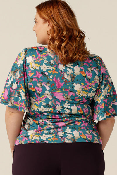 Curvy woman wearing a floral print jersey top with flutter sleeves. The top is made in Australia by Leina and Fleur, who specialise in quality tops, dresses and pants for petite to plus size women for work, travel and casual wear.