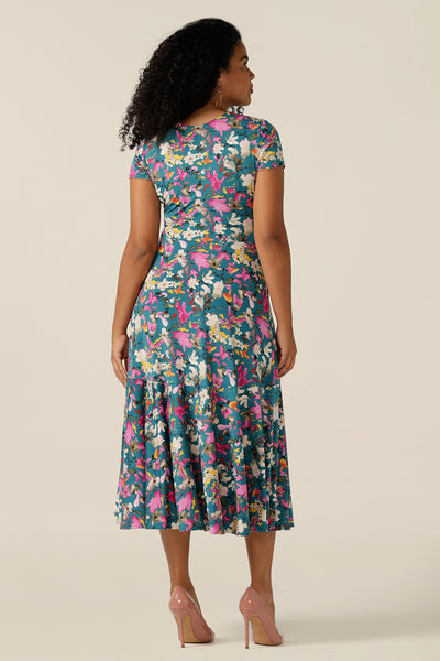 A woman wearing a fixed wrap jersey dress with short sleeves and a floral print. The dress features a maxi-length skirt with pockets. Made in Australia by women's clothing brand L&F, this wrap dress fits petite to curvy women.