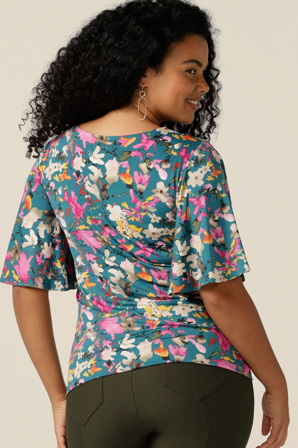 Size 12 woman wearing a floral print jersey top with flutter sleeves. The top is made in Australia by Leina and Fleur, who specialise in quality tops, dresses and pants for petite to plus size women for work, travel and casual wear.