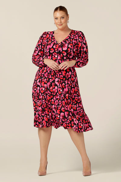 A plus size, size 18 woman wears a V-neck, empire line jersey dress with long sleeves. A good dress for day or night wear, the Alyssa Dress wears for work and corporate as well as as an evening and occasion wear dress. Made in Australia by Australia and New Zealand women's clothing label, Leina and Fleur