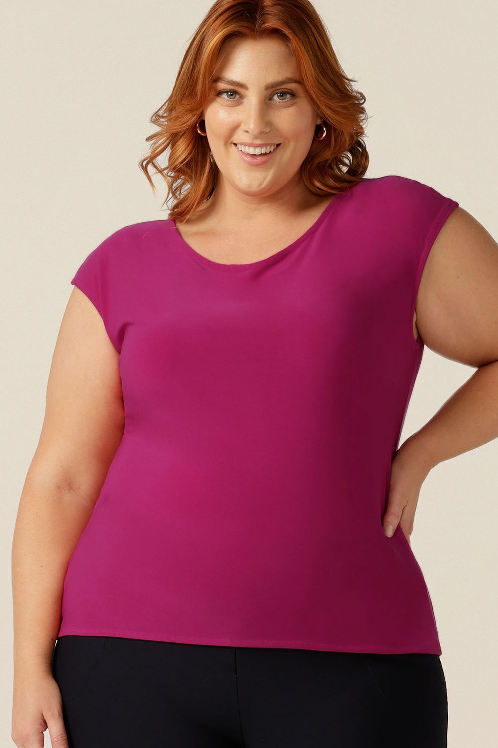 A curvy, size 18 woman wears a boat neck top with cap sleeves. In fuchsia pink jersey, it's a slim fit top that's made in Australia and available to shop online.