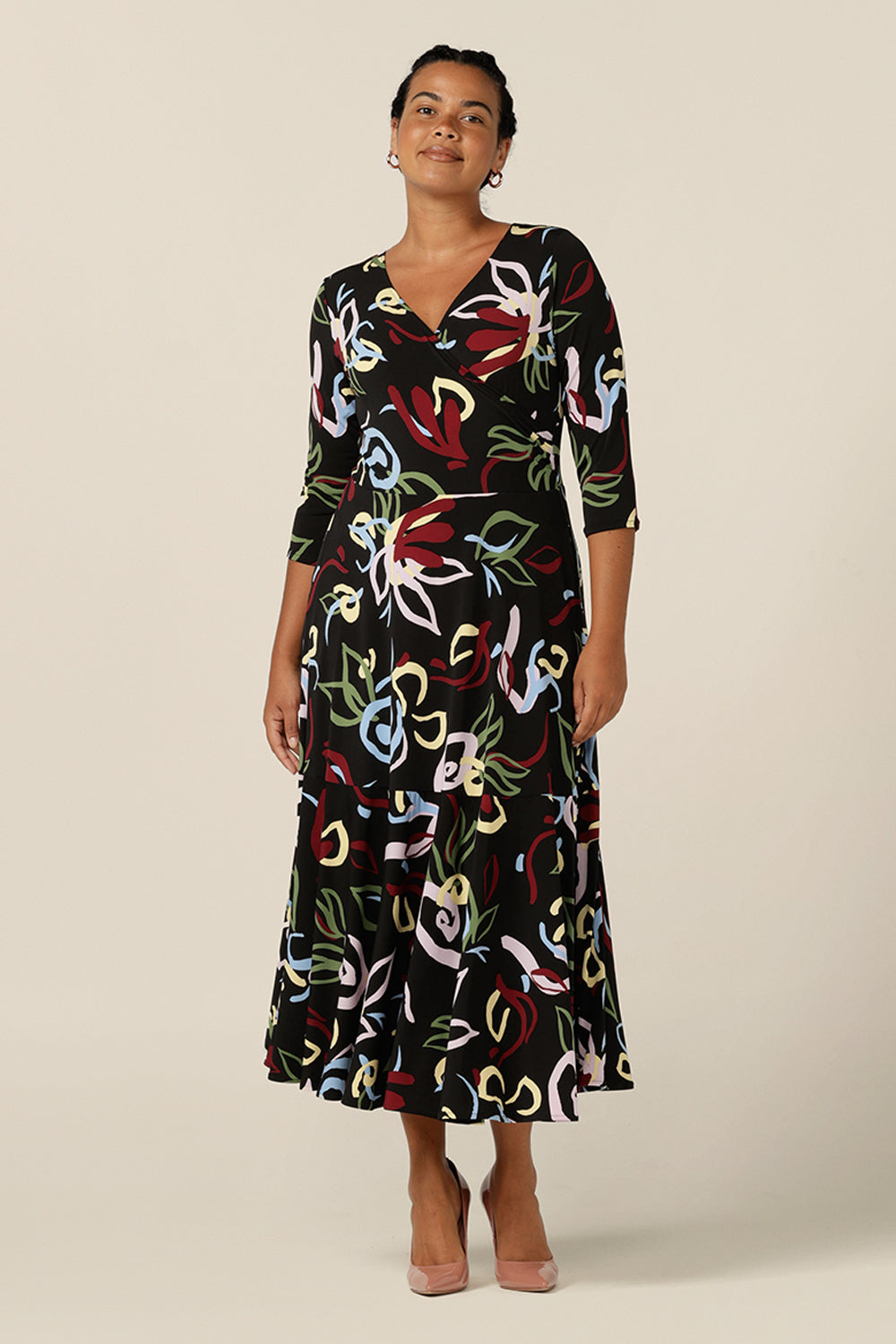 A size 12 woman wears a reversible wrap dress with 3/4 sleeves. Featuring a midi-length skirt with ruffle hem and 3/4 length sleeves, this printed jersey dress wears well as a work dress or everyday dress.