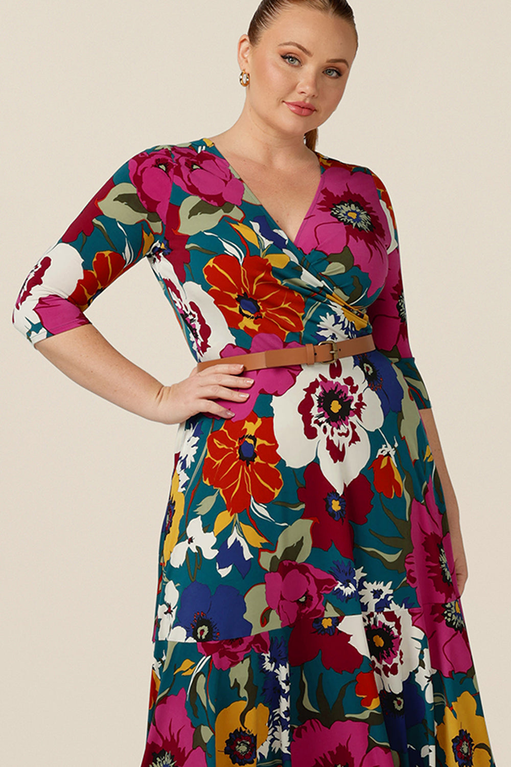 A close up of a reversible jersey maxi dress by Australian and New Zealand women's clothing company, L&F. The dress has a V-neckline, wrap front, 3/4 sleeves and side pockets in her full maxi skirt. Worn with a tan belt, this wrap dress style accentuates full and curvy figures.
