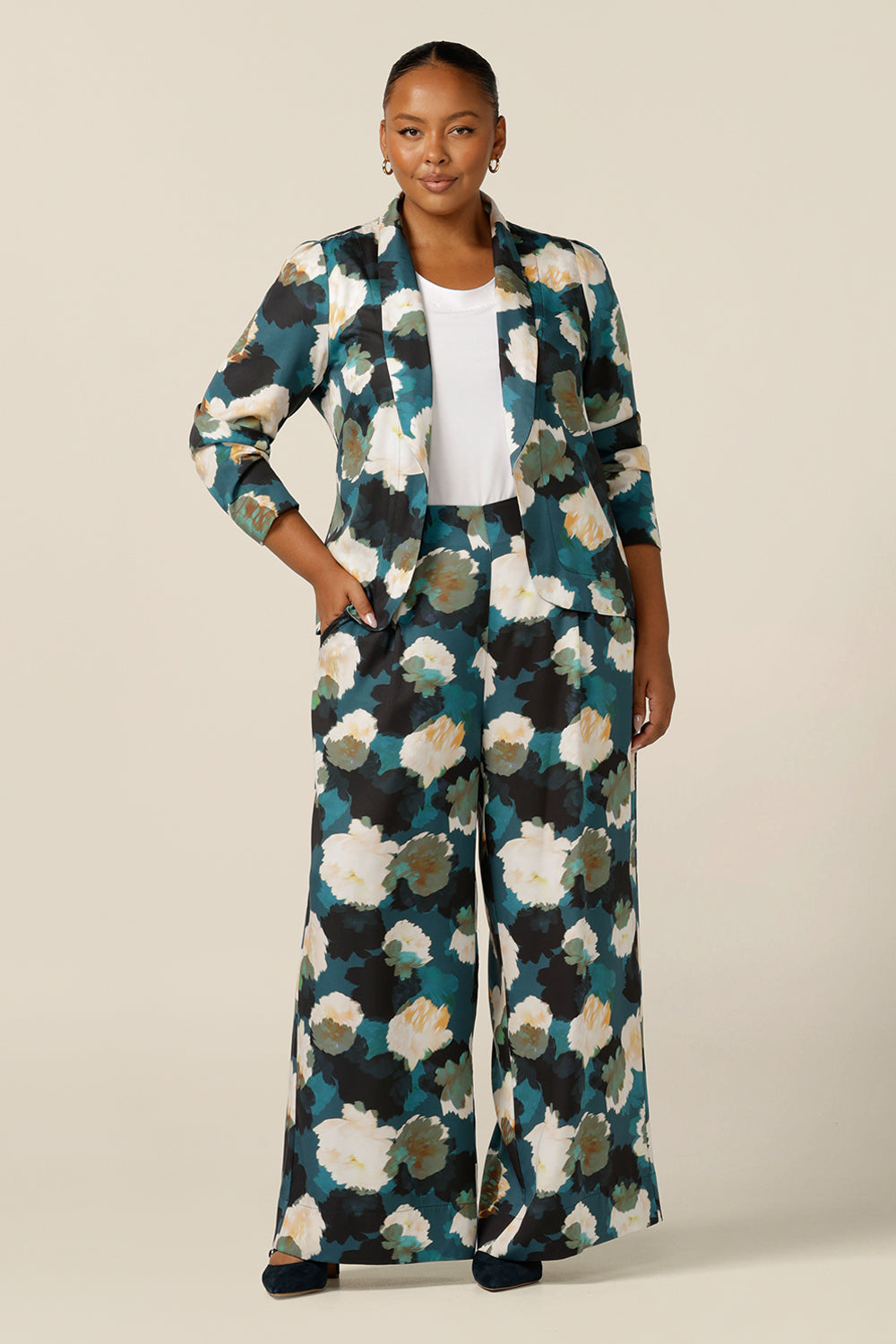 A size 18, plus size woman wears high-waisted printed wide-leg pants. Made in Australia from sustainable Tencel fabric, these eco-conscious trousers are part of women's clothing brand, elarroyoenterprises's focus on sustainable fashion. Worn with a printed soft tailored work blazer to create a corporate suit look for plus size and fuller figures.