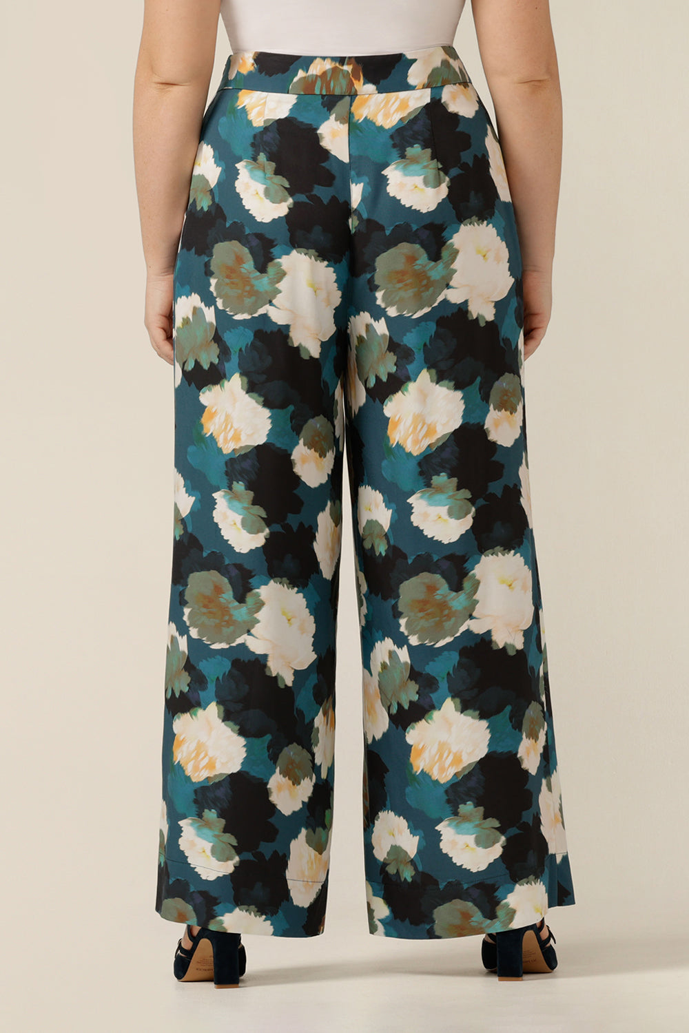 a size 12 woman wears high-waisted printed wide-leg trousers. Made in Australia from sustainable natural fibres, these luxury eco-conscious pants are part of women's clothing brand, elarroyoenterprises's focus on luxury sustainable fashion.