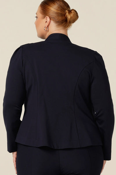 Back view of a size 18, fuller figure woman wearing a soft tailored navy jacket with navy work wear pants. Made in Australia for petite to plus sizes, the stretch ponte jersey is well-fitting on womanly curves.