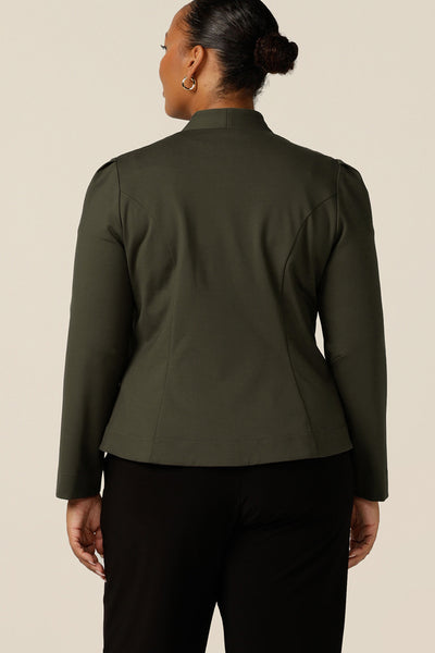 back view of a size 18, fuller figure woman wearing a tailored jacket with long sleeves, collarless V-neckline and zip fastening. Made in Australia in olive green ponte jersey, this is a quality-made, comfortable jacket for work and corporate wear.
