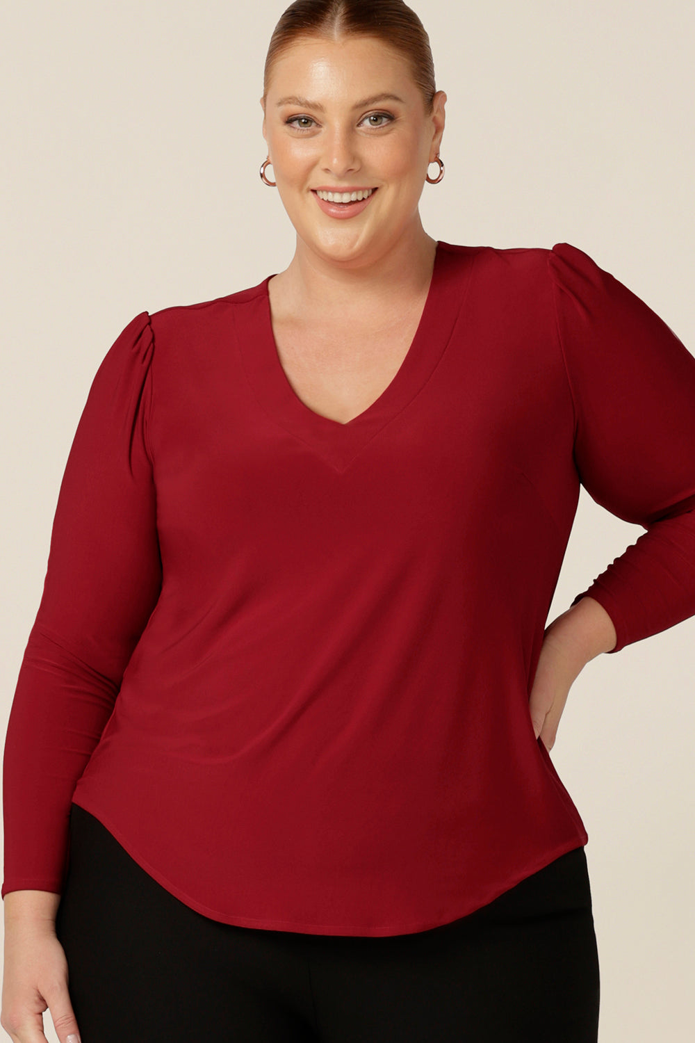 The perfect top for workwear and casual style, the Glyn Top in Flame red jersey features a V neck, shirttail hemline and long sleeves. Worn by a fuller figure, size 18 woman, this jersey top comes in an inclusive size range of sizes 8 - 24. 