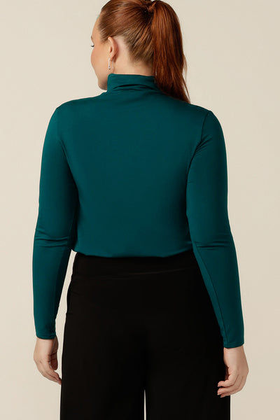 Back view of an Australian-made, women's long-sleeve, turtle neck top in petrol green bamboo jersey. A polo neck top for layering under tops and dresses for winter layering or corporate wear under work jackets.
