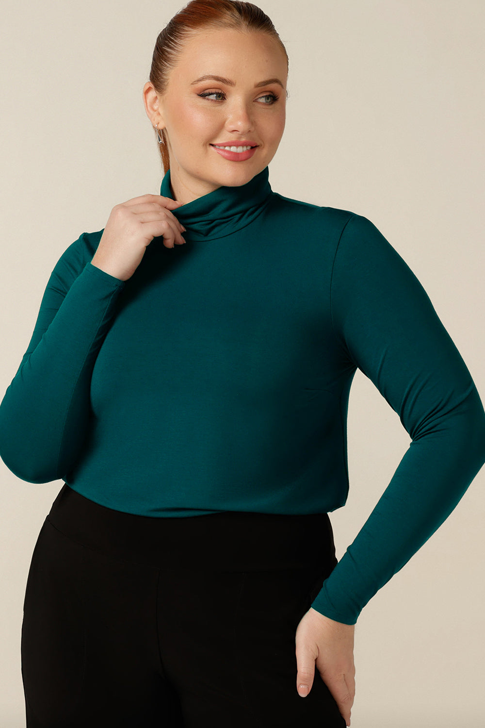 A size 12, curvy women wears a long-sleeve, turtle neck top in petrol green bamboo jersey. MAde in Australia by Australian and New Zealand women's clothing label, L&F this natural fibre top is lightweight and breathable - a goof top for winter layering!