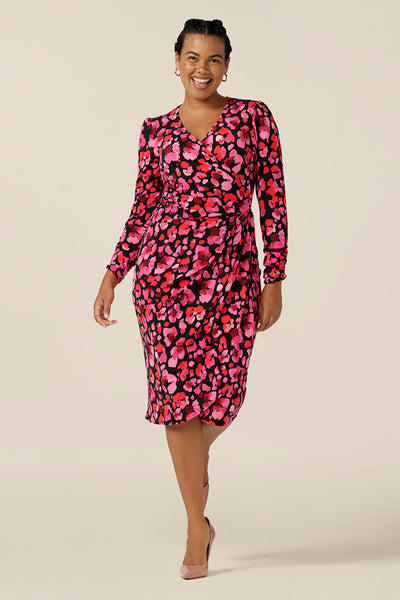 A curvy, size 12 woman wears a long sleeve wrap dress in floral print jersey. A classic dress, it's tulip skirt sits below the knee. Australian-made by Australia and New Zealand online clothing label, L&F, this wrap dress can be worn for workwear or as an event dress for date night style.