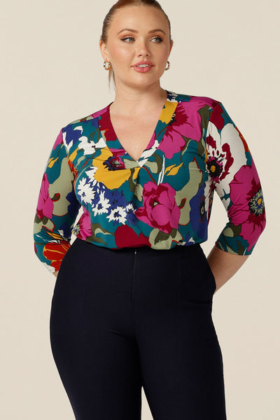 A curvy size 12 woman wears a jersey, V-neck top with 3/4 sleeves. Made-in Australia, this tailored top for work and corporate wear is available in an inclusive 8-24 size range.