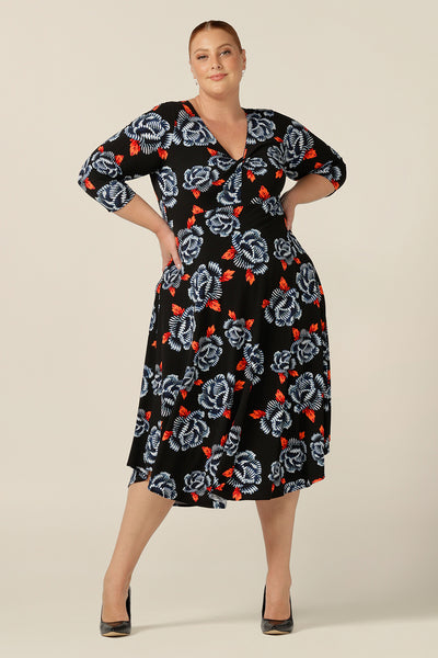 A size 18 fuller figure woman wears a blue and orange floral print jersey dress by Australian and New Zealand women's clothing brand, L&F. this empire line dress features a V-neckline with twist detail, 3/4 sleeves and a full below-the-knee-length skirt. Made in Australia, shop L&F work dresses in sizes 8 to size 24.