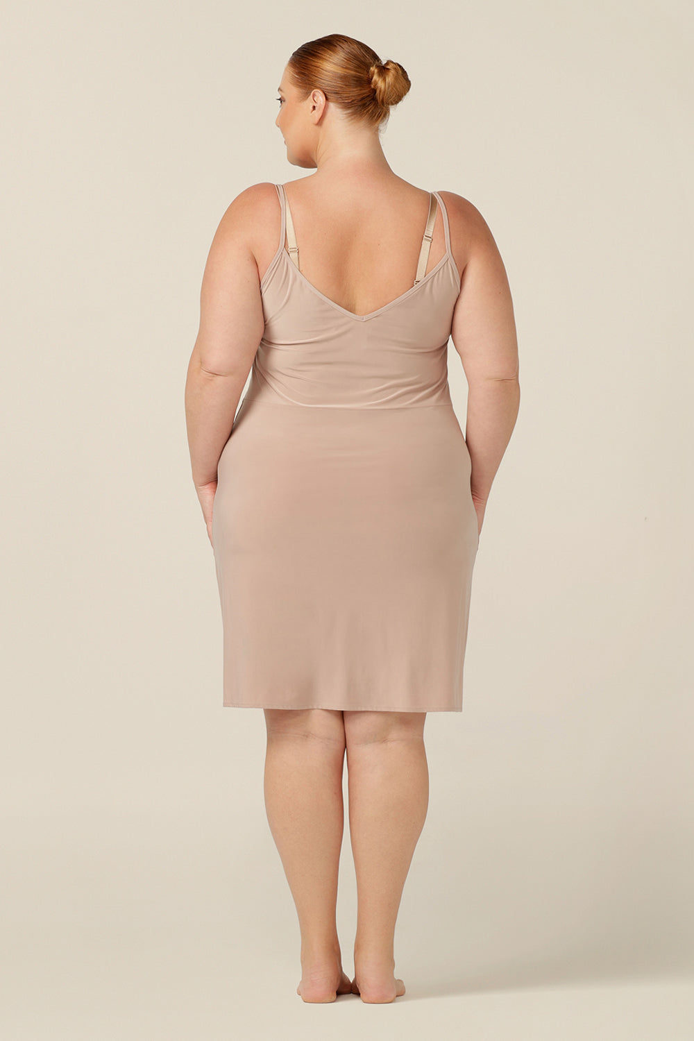 This Australian women's clothing piece is perfect for plus-size women in size 18 who are looking for a comfortable and versatile undergarment. It is a nude mini-length slip featuring a scoop neckline and thin straps that provide a smooth layer under dresses and skirts. Perfect as plus-size loungewear