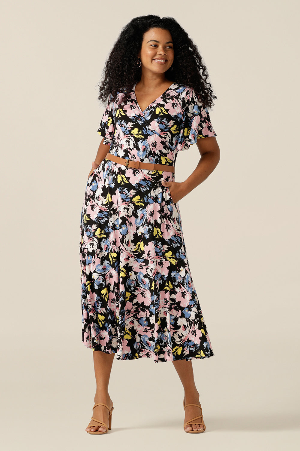 Vintage floral print dresses for women over 40, the Nicolle Reversible Dress is shown here on a size 12 curvy woman. A reversible style dress, she is worn here as wrap front with V-neckline but can worn with a boat neckline. A dress with arm coverage, it has short sleeves and a full midi-length skirt. A dress for feminine corporate dressing and work attire, this dress comes in sizes 8 to sizes 24.  