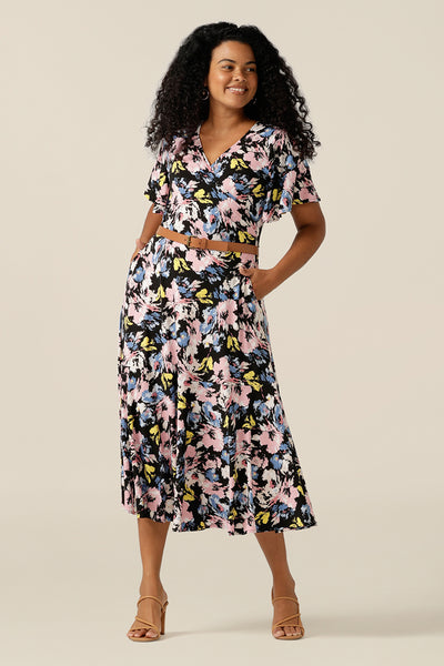 Vintage floral print dresses for women over 40, the Nicolle Reversible Dress is shown here on a size 12 curvy woman. A reversible style dress, she is worn here as wrap front with V-neckline but can worn with a boat neckline. A dress with arm coverage, it has short sleeves and a full midi-length skirt. A dress for feminine corporate dressing and work attire, this dress comes in sizes 8 to sizes 24.  