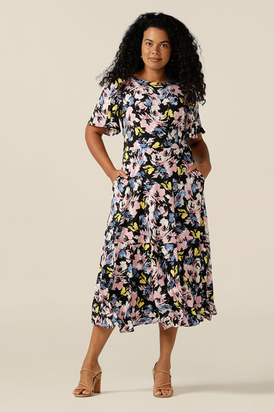 Vintage floral print dresses for women over 40, the Nicolle Reversible Dress is shown here on a size 12 curvy woman. A reversible style dress, she is worn here as wrap front with V-neckline but can worn with a boat neckline. A dress with arm coverage, it has short sleeves and a full midi-length skirt. A dress for feminine corporate dressing and work attire, this dress comes in sizes 8 to sizes 24.