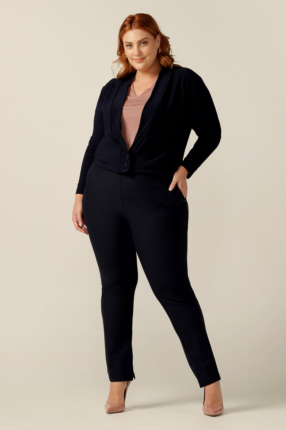 A plus size woman wears a soft navy jacket in a size 18. The best jacket for autumn/winter, this long sleeves 2-button cover-up is a as comfortable as a cardigan but with a corporate edge that transitions for work wear. 
