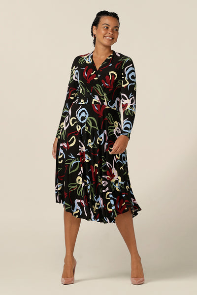 A size 12 woman wears a jersey work dress with wrap-over bodice, dipped hem and full length sleeves made by Australian and New Zealand women's clothing brand,L&F.