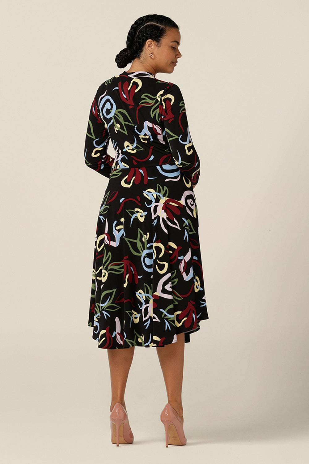 Back view of a woman wearing a knee-length, jersey, work dress with long sleeves in a size 12. In printed jersey, abstract patterns add colour to the black base of this comfortable dress.