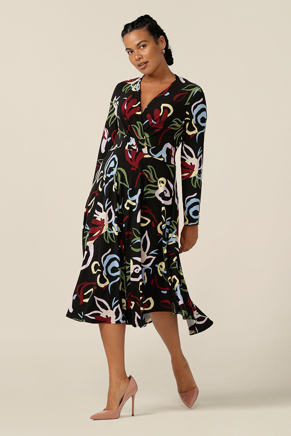 Back view of a size 12 woman wearing a knee-length, jersey, work dress with long sleeves. In printed jersey, abstract patterns add colour to the black base of this Australian-made dress.