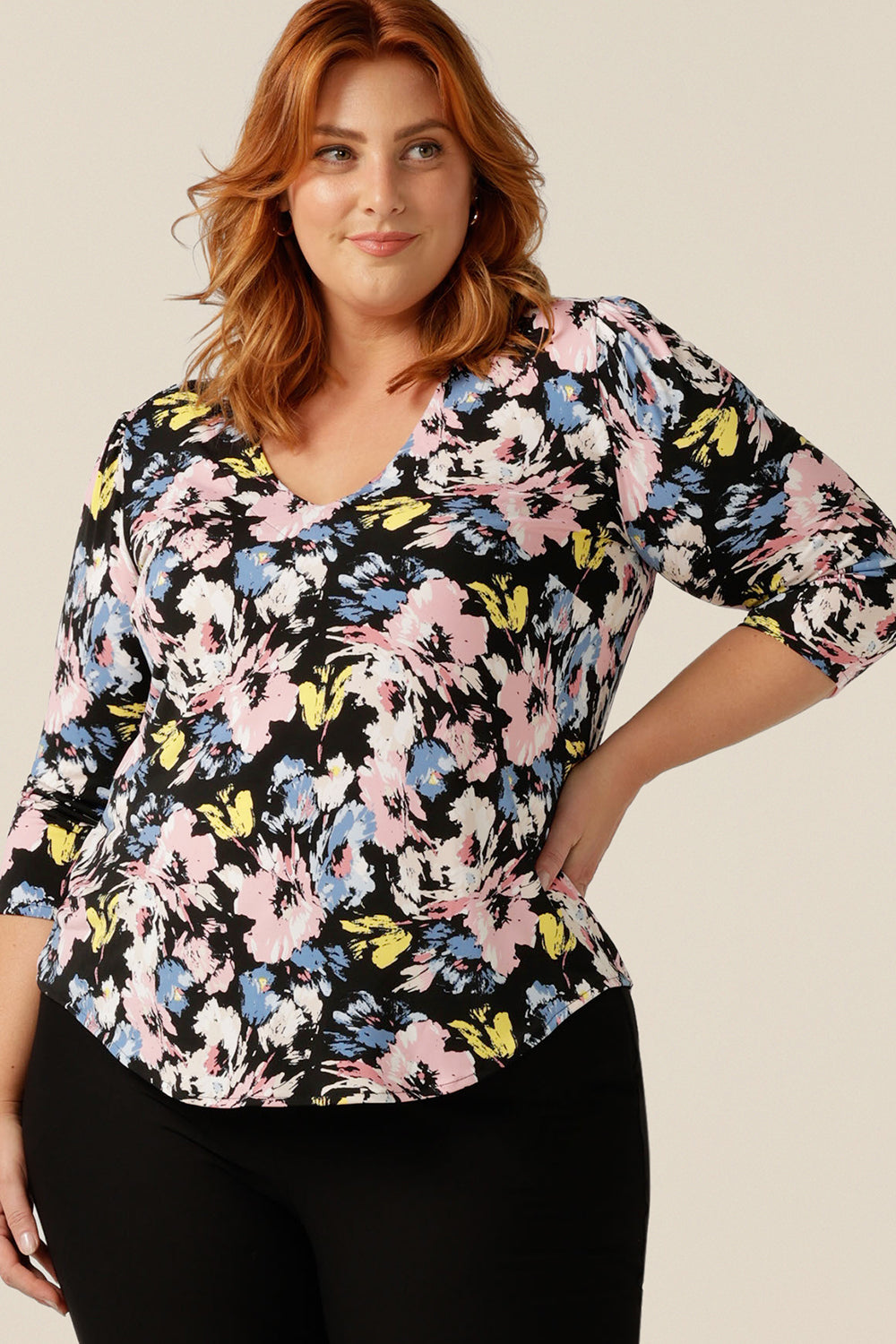 a curvy size 18 woman wears a V-neck top with 3/4 sleeve. In pastel colours, a vintage floral print patterns this jersey top's stretch fabric. Made in Australia, this quality top for work or casual wear, is designed to fit women from sizes 8 to size 18.